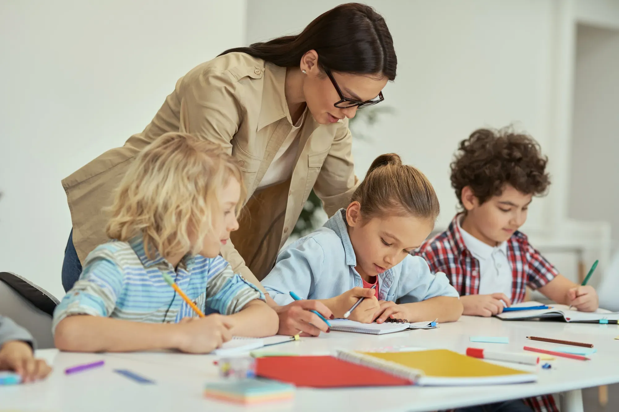 Lehrerin unterstützt mehrere Kinder im Unterricht